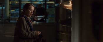 Movie still from “The Debt” (2010), directed by John Madden – A woman holding a purse in a dark room; Medium shot, Over the shoulder angle