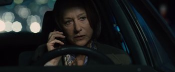 Movie still from “The Debt” (2010), directed by John Madden – A woman sitting in the driver's seat of a car talking on a cell phone; Close Up shot, Over the shoulder angle