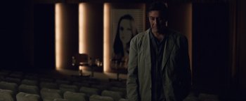 Movie still from “The Debt” (2010), directed by John Madden – A man standing in front of a picture of a woman; Medium shot, Low angle