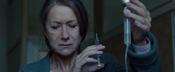 Movie still from “The Debt” (2010), directed by John Madden – An older woman holding a syringe in her hand; Close Up shot, Low angle