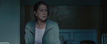 Movie still from “The Debt” (2010), directed by John Madden – A woman standing in a room looking at the camera; Close Up shot, Over the shoulder angle