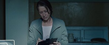 Movie still from “The Debt” (2010), directed by John Madden – A woman writing on a piece of paper in a dark room; Close Up shot, Over the shoulder angle