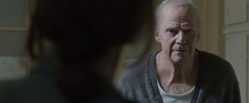 Movie still from “The Debt” (2010), directed by John Madden – An old man with a white beard is looking at the camera; Close Up shot, Over the shoulder angle