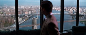 Movie still from “The Devil's Advocate” (1997), directed by Taylor Hackford – A man standing in front of a window overlooking a city; Extreme Wide shot, Over the shoulder angle