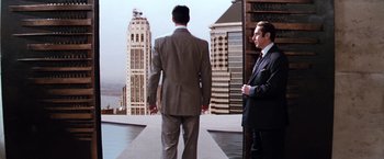 Movie still from “The Devil's Advocate” (1997), directed by Taylor Hackford – A man in a suit standing next to another man in a business suit; Wide shot, Over the shoulder angle