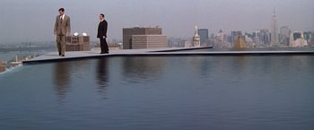 Movie still from “The Devil's Advocate” (1997), directed by Taylor Hackford – A man in a suit standing on the edge of a swimming pool; Extreme Wide shot, High angle