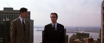 Movie still from “The Devil's Advocate” (1997), directed by Taylor Hackford – A man in a suit and tie standing in front of a body of water; Medium shot, Low angle
