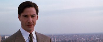 Movie still from “The Devil's Advocate” (1997), directed by Taylor Hackford – A man wearing a suit and tie standing in front of a city; Close Up shot, Over the shoulder angle