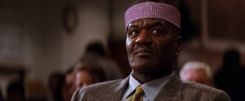 Movie still from “The Devil's Advocate” (1997), directed by Taylor Hackford – An older man wearing a purple hat and a suit; Close Up shot, Low angle