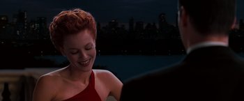 Movie still from “The Devil's Advocate” (1997), directed by Taylor Hackford – A woman in a red dress smiling at a man in a black suit; Close Up shot, Over the shoulder angle