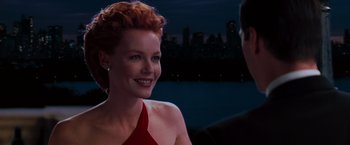 Movie still from “The Devil's Advocate” (1997), directed by Taylor Hackford – A woman in a red dress smiling at a man in a black suit; Close Up shot, Over the shoulder angle