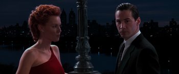 Movie still from “The Devil's Advocate” (1997), directed by Taylor Hackford – A man and a woman standing next to each other in front of a city skyline at night; Medium shot, Over the shoulder angle