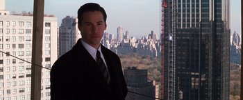 Movie still from “The Devil's Advocate” (1997), directed by Taylor Hackford – A man wearing a suit and tie standing in front of a city skyline; Medium shot, Low angle
