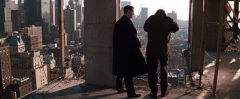 Movie still from “The Devil's Advocate” (1997), directed by Taylor Hackford – Two men standing next to each other near a building; Wide shot, Low angle