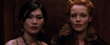 Movie still from “The Devil's Advocate” (1997), directed by Taylor Hackford – Two women standing next to each other in front of a wooden wall; Close Up shot, Low angle