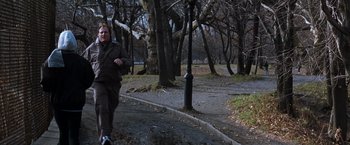 Movie still from “The Devil's Advocate” (1997), directed by Taylor Hackford – A man is running in a park on a rainy day; Wide shot, Over the shoulder angle