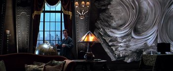 Movie still from “The Devil's Advocate” (1997), directed by Taylor Hackford – A man standing next to a table with a lamp on top of it; Wide shot, Low angle