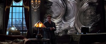 Movie still from “The Devil's Advocate” (1997), directed by Taylor Hackford – A man standing in front of a lamp in a room; Medium shot, Low angle