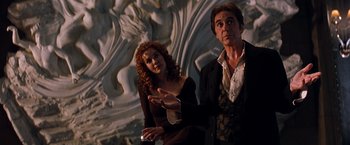 Movie still from “The Devil's Advocate” (1997), directed by Taylor Hackford – A man and a woman are standing next to each other; Medium shot, Over the shoulder angle