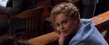 Movie still from “The Devil's Advocate” (1997), directed by Taylor Hackford – A woman sitting at a table with her head resting on her hand; Close Up shot, Over the shoulder angle