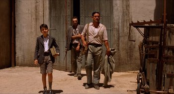 Movie still from “The Devil's Backbone” (2001), directed by Guillermo del Toro – A group of men walking down a street; Wide shot, Low angle