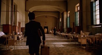 A man walking down a hall way with a suitcase
