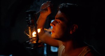 Movie still from “The Devil's Backbone” (2001), directed by Guillermo del Toro – A man lighting a cigarette in the dark with an oil lamp in front of him; Close Up shot, Low angle