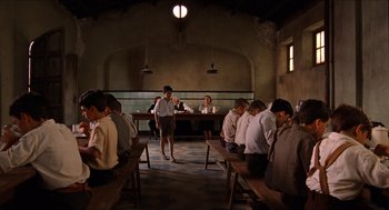 Movie still from “The Devil's Backbone” (2001), directed by Guillermo del Toro – A group of people sitting around a room; Wide shot, High angle