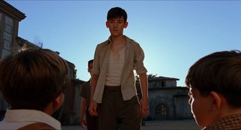 Movie still from “The Devil's Backbone” (2001), directed by Guillermo del Toro – A young man standing in front of a brick building; Medium shot, Low angle