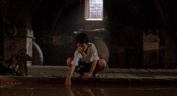 Movie still from “The Devil's Backbone” (2001), directed by Guillermo del Toro – A young man sitting on the ground near a window; Wide shot, Low angle