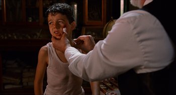 Movie still from “The Devil's Backbone” (2001), directed by Guillermo del Toro – A man is putting a brush on a young boy's face; Close Up shot, Over the shoulder angle