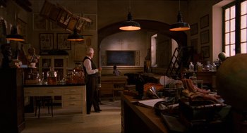 Movie still from “The Devil's Backbone” (2001), directed by Guillermo del Toro – An older man standing in a room with a large desk; Wide shot, High angle