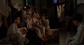 Movie still from “The Devil's Backbone” (2001), directed by Guillermo del Toro – A group of people sitting on top of a wooden box; Wide shot, High angle