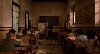 Movie still from “The Devil's Backbone” (2001), directed by Guillermo del Toro – A woman standing in front of a chalkboard in a classroom; Wide shot, High angle