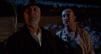Movie still from “The Devil's Backbone” (2001), directed by Guillermo del Toro – A man and a man standing next to each other in front of a wall; Medium shot, Low angle