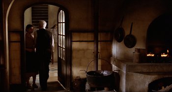 Movie still from “The Devil's Backbone” (2001), directed by Guillermo del Toro – An old man standing in a kitchen with a pot on the stove; Wide shot, Over the shoulder angle