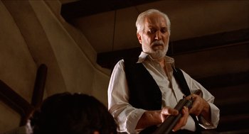 Movie still from “The Devil's Backbone” (2001), directed by Guillermo del Toro – An older man with a beard is holding a gun; Medium shot, Low angle