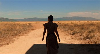 Movie still from “The Devil's Backbone” (2001), directed by Guillermo del Toro – A woman walking down a dirt road in the desert; Extreme Wide shot, Over the shoulder angle