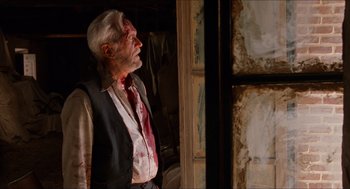 Movie still from “The Devil's Backbone” (2001), directed by Guillermo del Toro – An old man with a bloody face standing in front of a window; Medium shot, Low angle