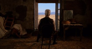 Movie still from “The Devil's Backbone” (2001), directed by Guillermo del Toro – An older man sitting in a chair looking out a window; Wide shot, Low angle