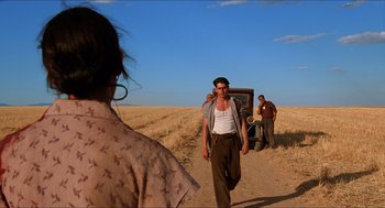 Movie still from “The Devil's Backbone” (2001), directed by Guillermo del Toro – A man and a woman walking down a dirt road near an old car; Wide shot, Low angle
