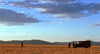 Movie still from “The Devil's Backbone” (2001), directed by Guillermo del Toro – A group of people standing on top of a dry grass field; Extreme Wide shot, Low angle