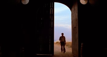 Movie still from “The Devil's Backbone” (2001), directed by Guillermo del Toro – A man standing in front of an open door; Wide shot, Low angle