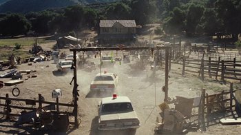 Movie still from “The Devil's Rejects” (2005), directed by Rob Zombie – Cars driving down a dusty road near a house; Extreme Wide shot, High angle