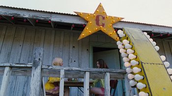 Movie still from “The Devil's Rejects” (2005), directed by Rob Zombie – Two girls sitting on a porch with a star; Wide shot, Low angle