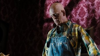 Movie still from “The Devil's Rejects” (2005), directed by Rob Zombie – An old man with a bald head wearing overalls; Medium shot, Low angle