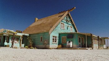 Movie still from “The Devil's Rejects” (2005), directed by Rob Zombie – A house with a thatched roof on a dirt road; Extreme Wide shot, Low angle