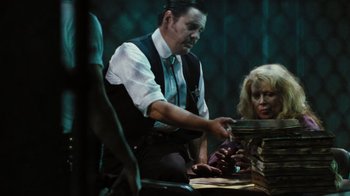 Movie still from “The Devil's Rejects” (2005), directed by Rob Zombie – A man and a woman sitting at a table with papers; Medium shot, Over the shoulder angle