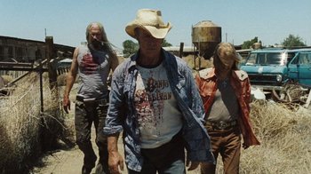 Movie still from “The Devil's Rejects” (2005), directed by Rob Zombie – A group of people walking on a dirt field; Medium shot, Low angle