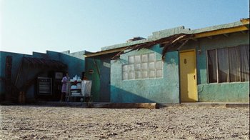 Movie still from “The Devil's Rejects” (2005), directed by Rob Zombie – A person standing outside of a building with a cart; Extreme Wide shot, Low angle